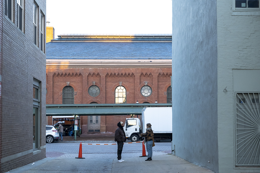 Two people chatting in an alley opposite Eastern Market.