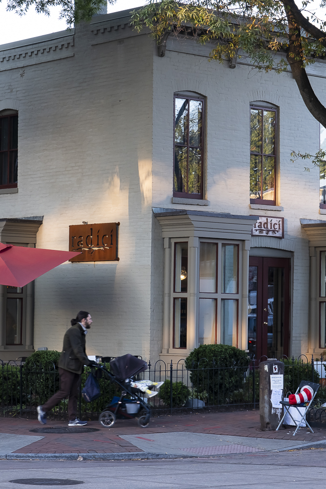 Dad walking with a stroller past Radici market.